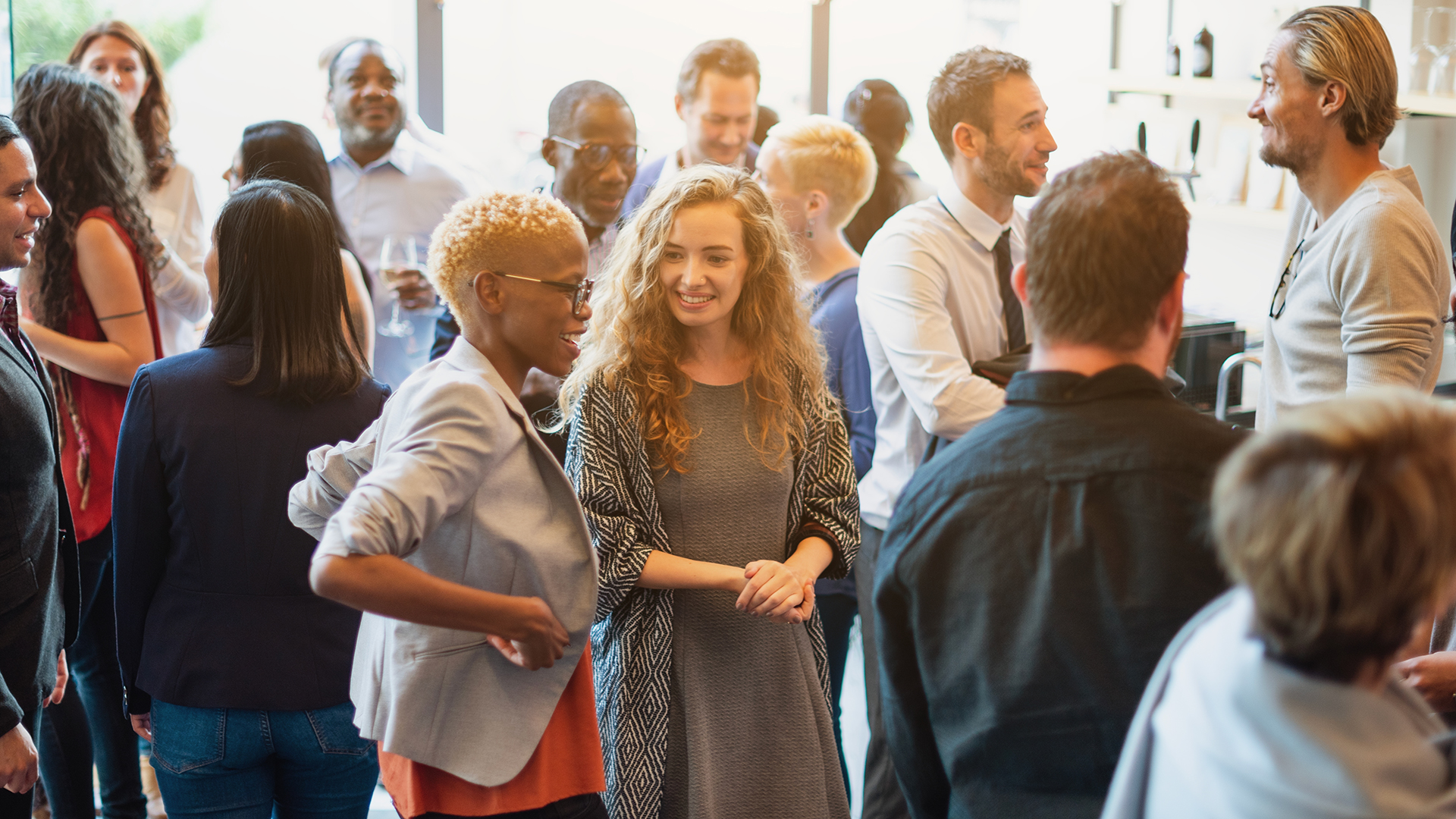 Diverse group of people socializing at a casual gathering. Men and women of various ethnicities engaged in conversation, enjoying a lively social event. Diverse people mingle at a social event.